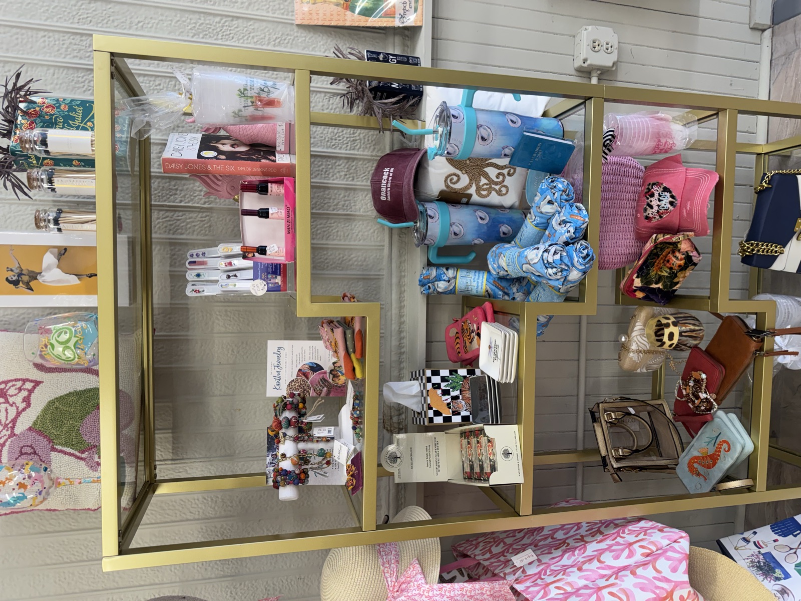 The gold shelf stacked with gifts, caps, and tumblers